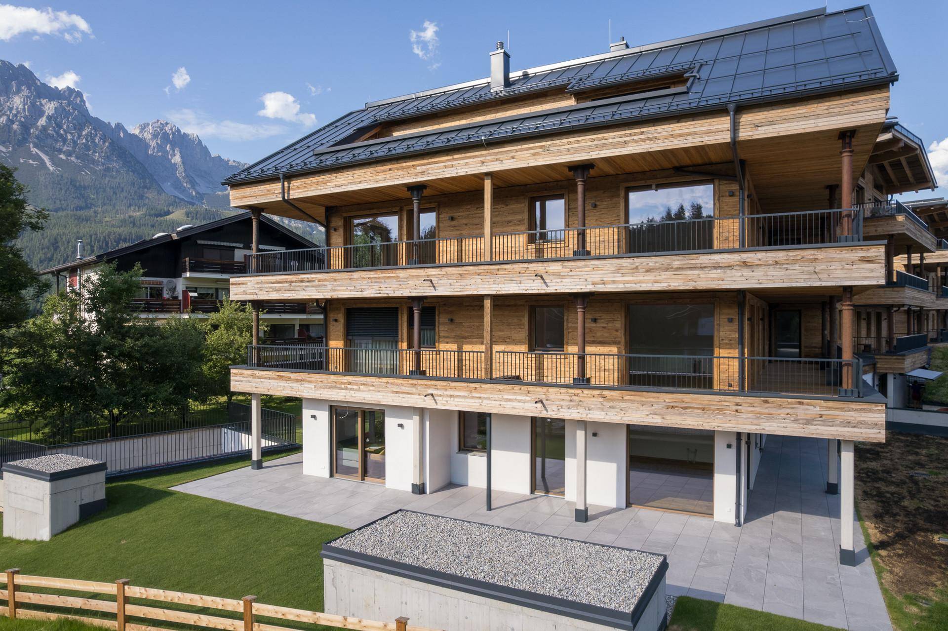 Erdgeschosswohnungen mit direktem Zugang zu einer gepflasterten Terrasse und einem kleinen Rasenbereich.
