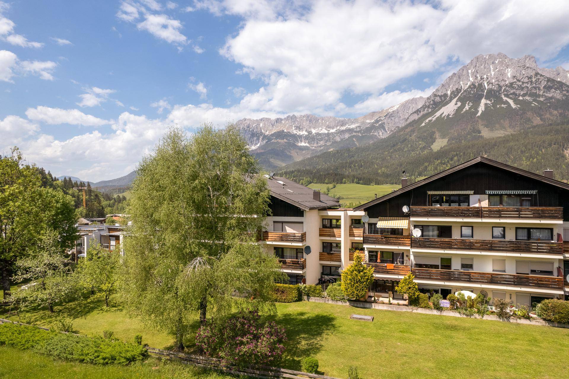 Blick auf die umliegenden Gebäude und die beeindruckende Bergkulisse mit üppiger Vegetation.