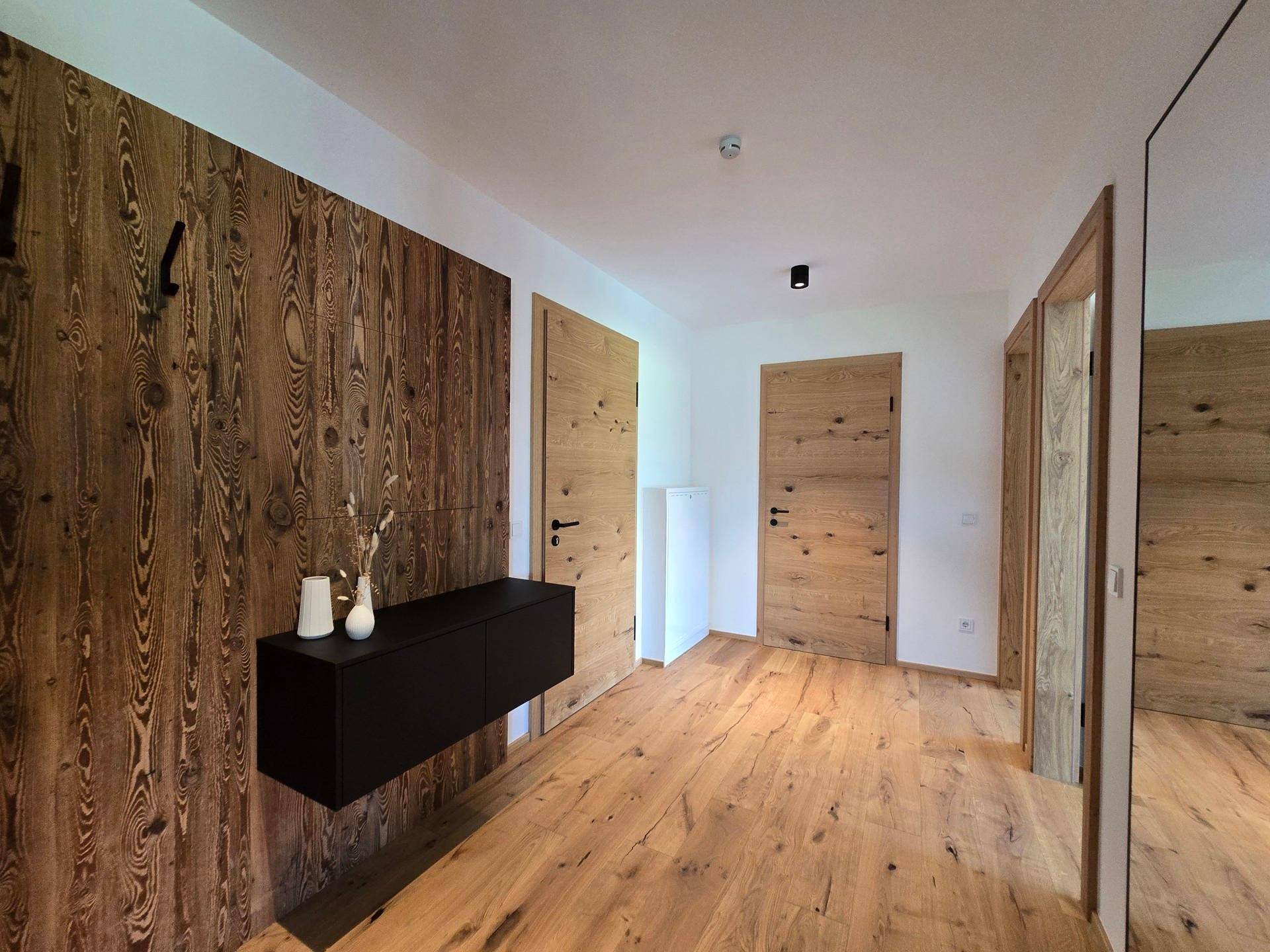 Geräumiger Flur mit Holzwänden und Holztüren, der zu den weiteren Räumen führt.