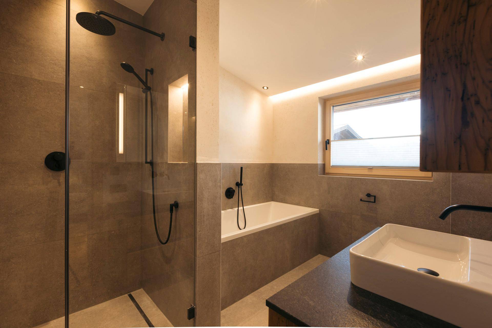 Modernes Badezimmer mit begehbarer Dusche, integrierter Badewanne und stilvollem Aufsatzwaschbecken.