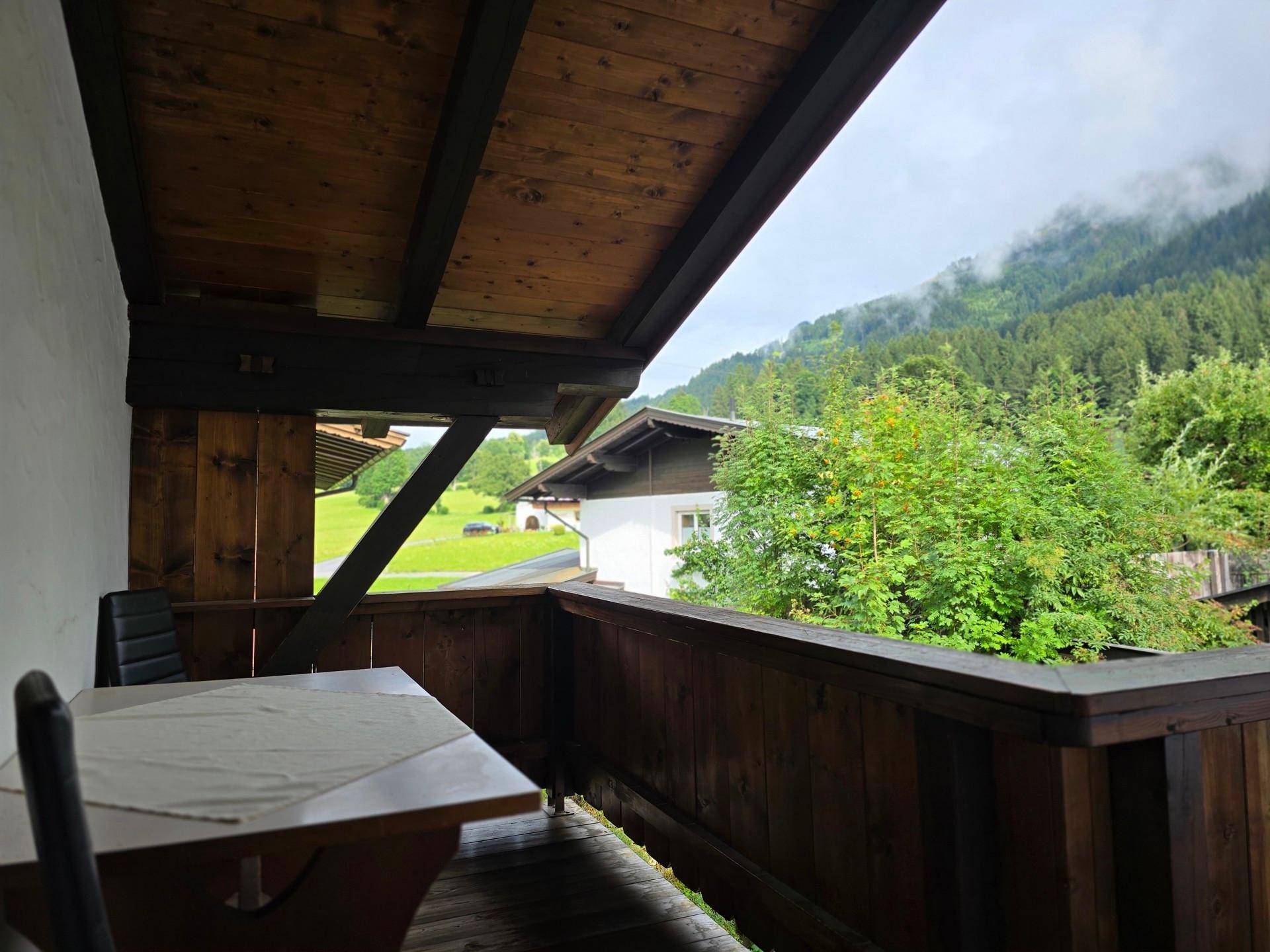 Kleiner Holzbalkon mit Tisch und Stuhl, bietet einen ruhigen Blick auf die grüne Umgebung.