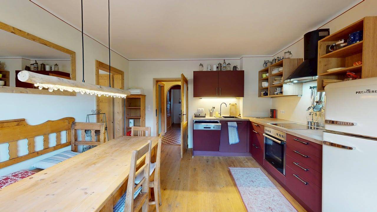 Offene Küche mit Essbereich, roten Schränken und Holzmöbeln, ideal für gesellige Mahlzeiten.