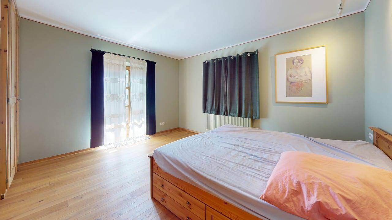 Schlafzimmer mit Holzboden, großem Bett mit Stauraum und einem Kleiderschrank.