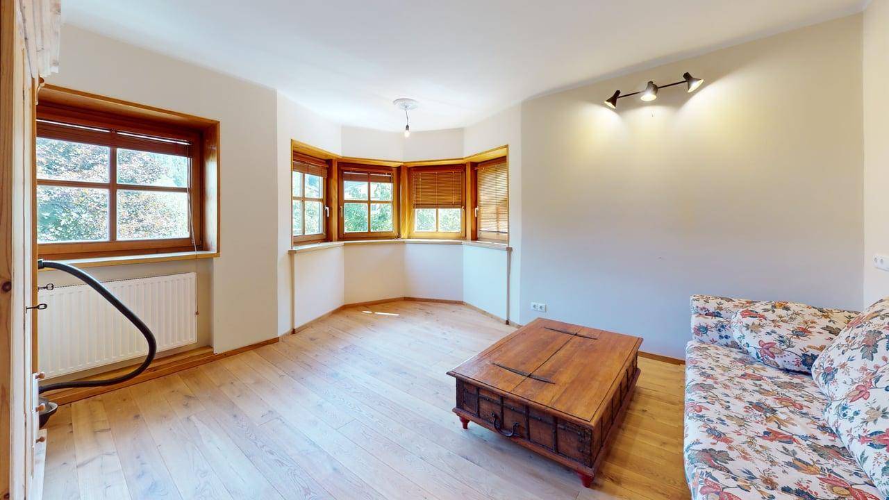 Heller Wohnraum mit Erkerfenstern, Holzboden und einem rustikalen Couchtisch.
