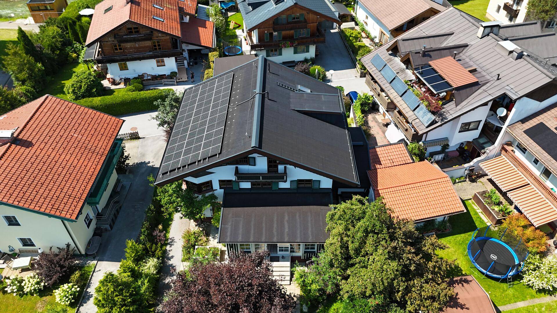 Luftaufnahme des Hauses mit Solaranlage auf dem Dach, umgeben von weiteren Wohnhäusern.