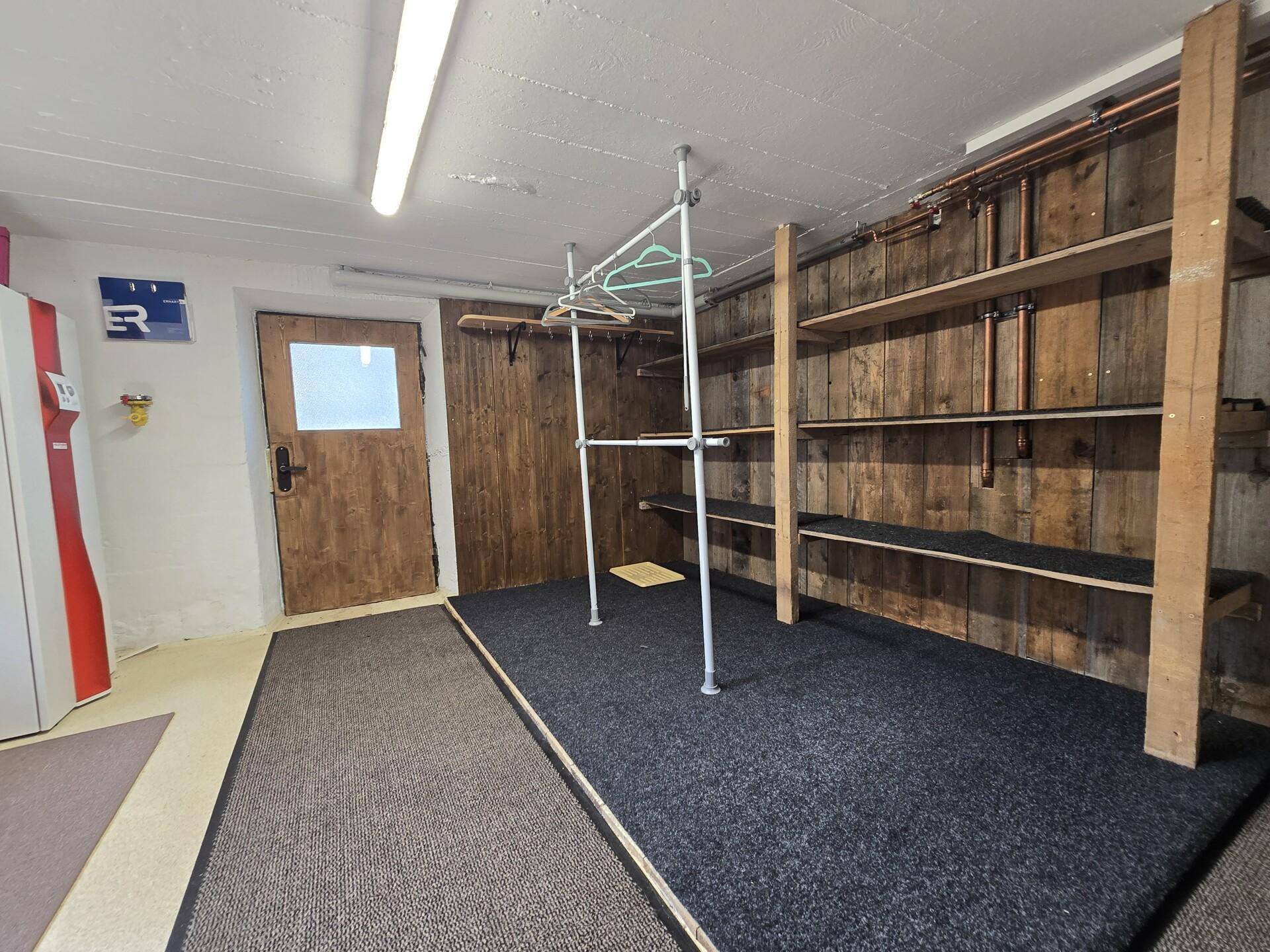 Geräumiger Kellerraum mit Holzregalen und Teppichboden, ideal für Lagerung und Organisation.