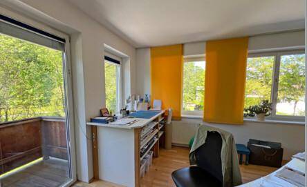 Kleines Büro mit Zugang zu einem Balkon, Schreibtisch und Blick ins Grüne.