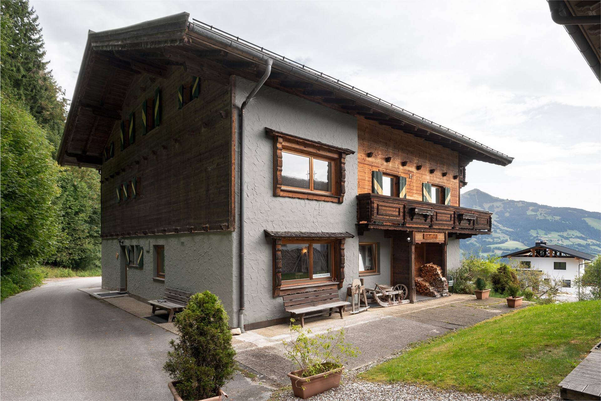 Seitenansicht des traditionellen Hauses mit Holzbalkonen, Holzfassade und Blick auf die Berge.
