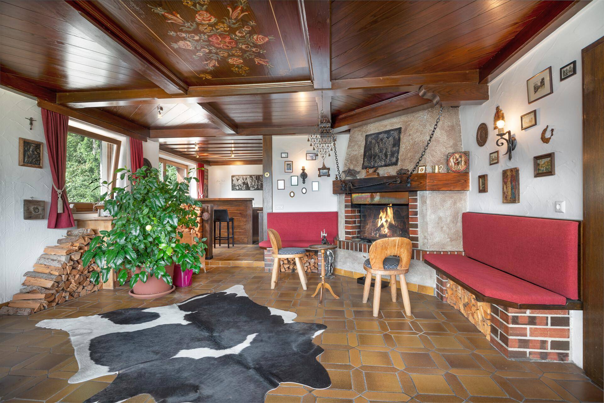 Rustikales Wohnzimmer mit Kamin, Holzbalkendecke und traditioneller Einrichtung, ideal für gemütliche Abende.