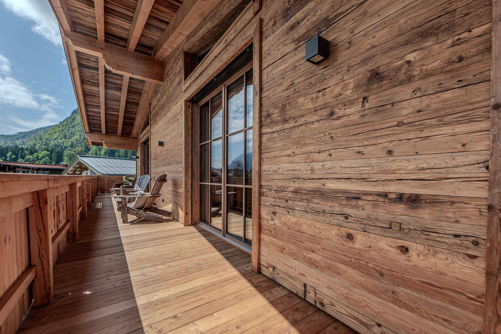 Rustikaler Holzbalcon mit großen Glasfenstern, die viel Licht ins Innere lassen und Bergblick bieten.