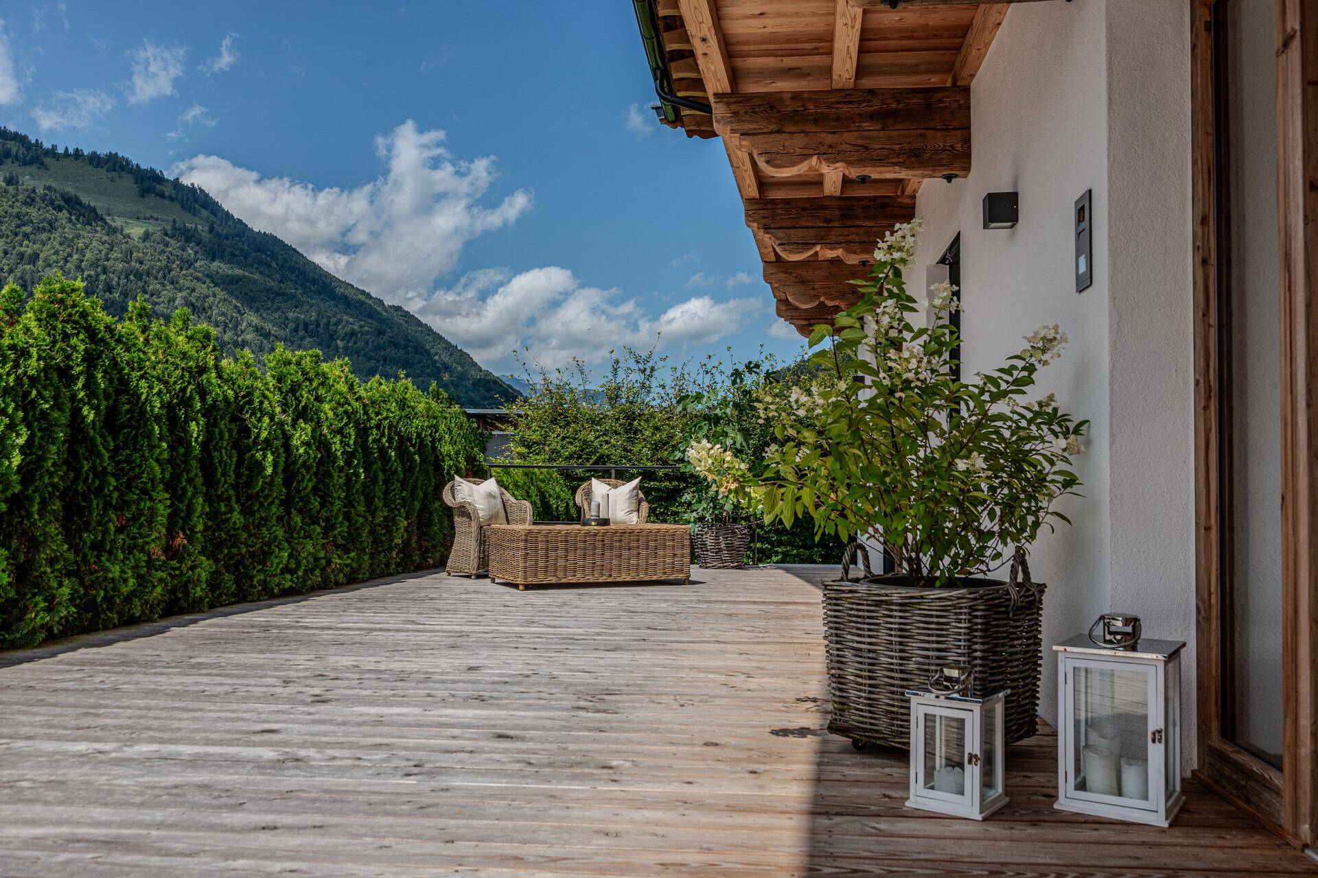 Geräumige Holzterrasse mit stilvollen Korbmöbeln und Pflanzen, ideal für entspannte Stunden im Freien.