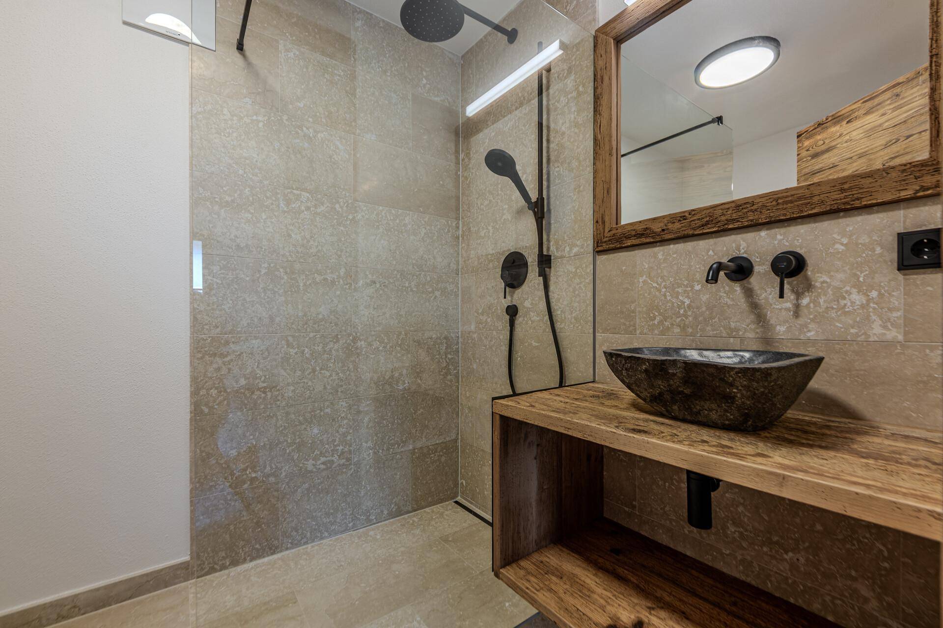 Modernes Badezimmer mit ebenerdiger Dusche, Natursteinwaschbecken und rustikalem Holzwaschtisch.