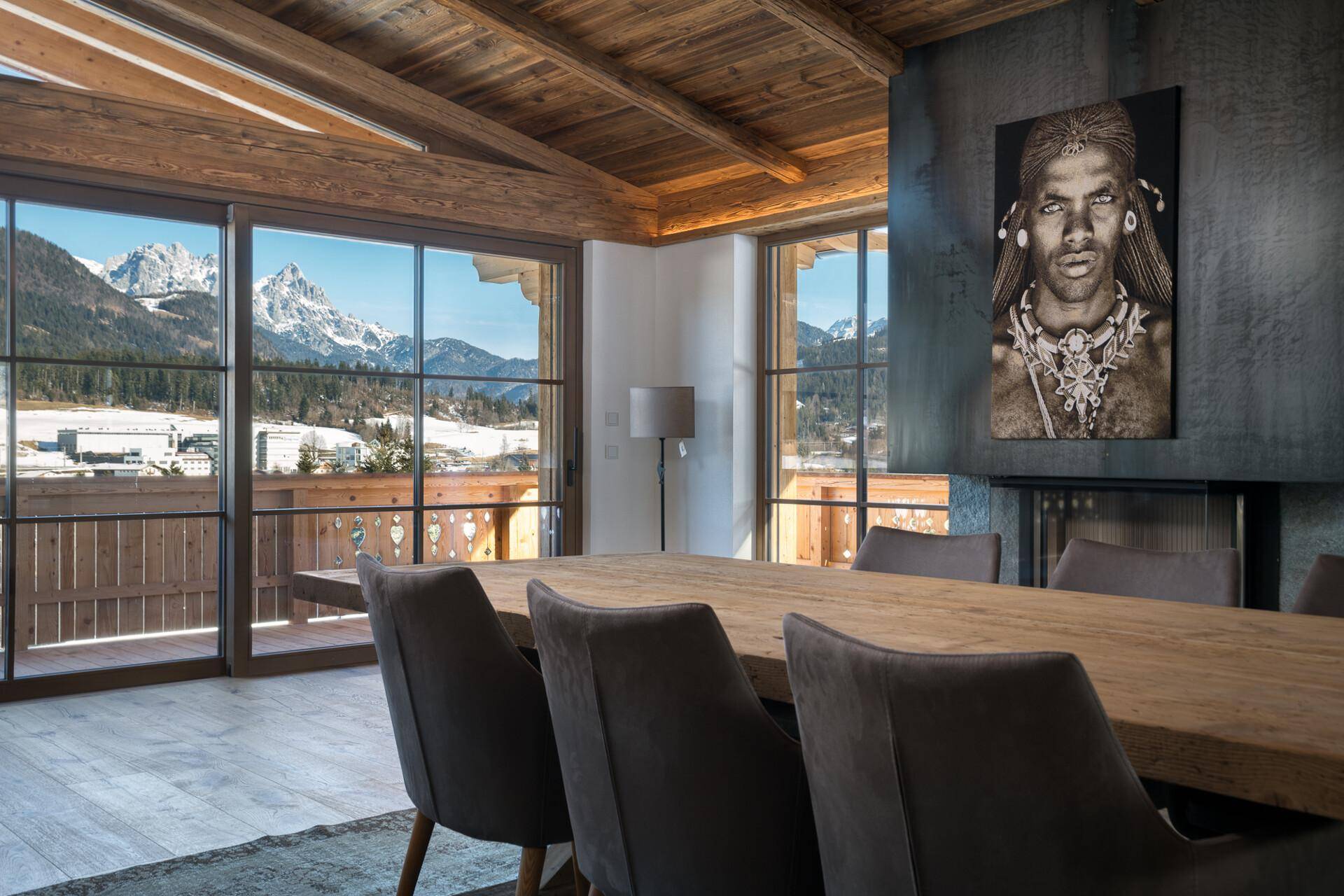 Essbereich mit Holztisch, modernen Stühlen und beeindruckendem Bergblick durch große Fenster.
