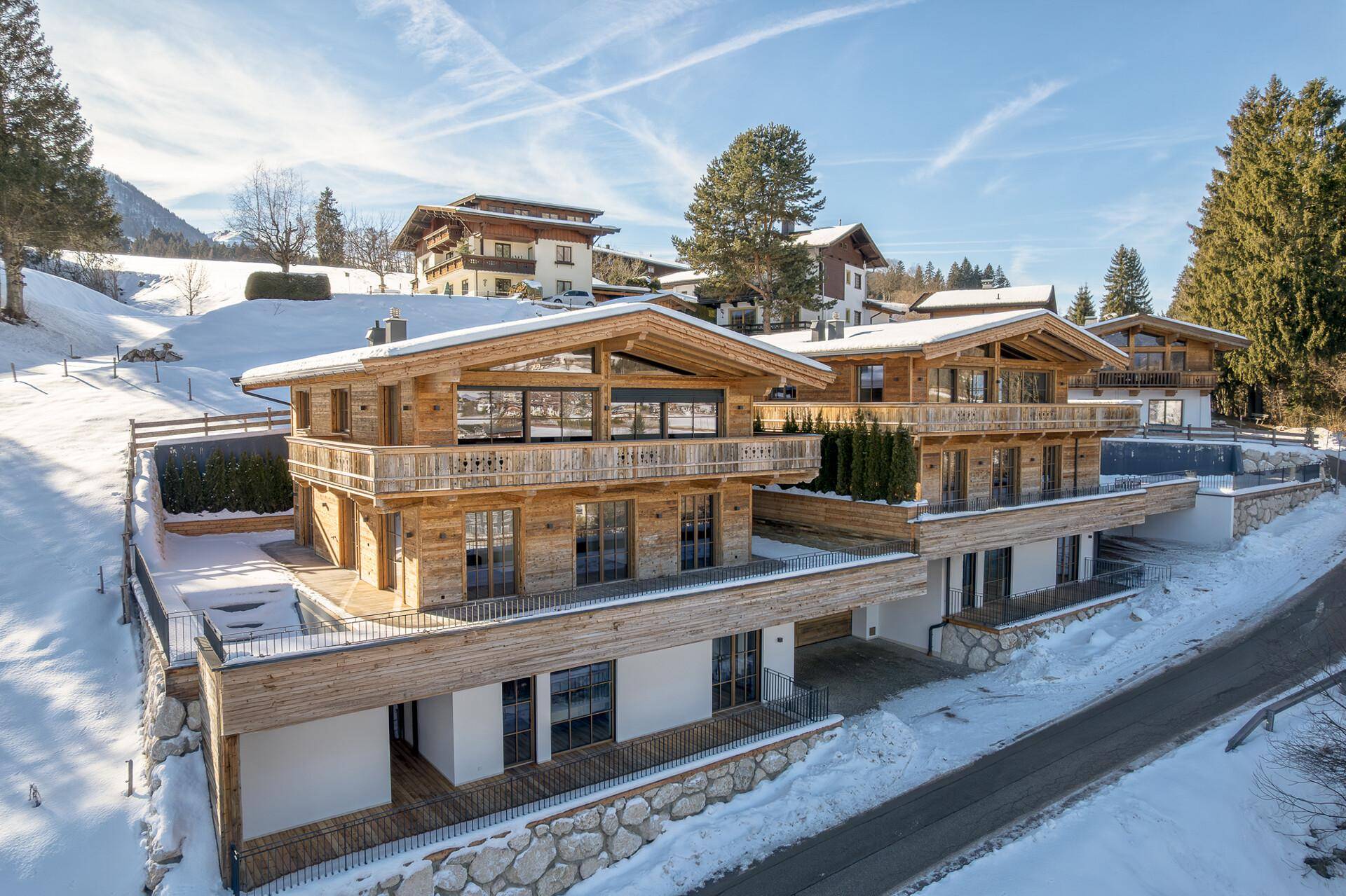 Luxuriöse Chalets in alpiner Umgebung mit großen Balkonen und verschneiter Landschaft.