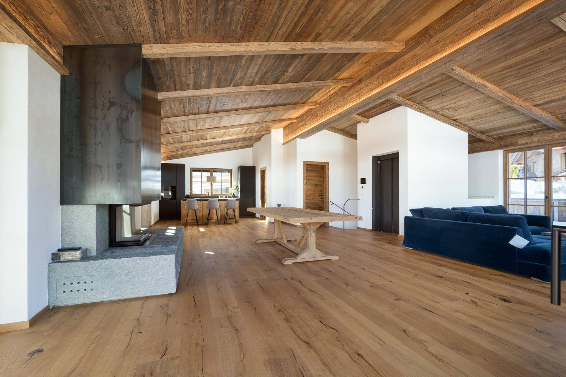 Geräumiger offener Wohnbereich mit Kamin, Holzbalkendecke und Essbereich, ideal für geselliges Beisammensein.