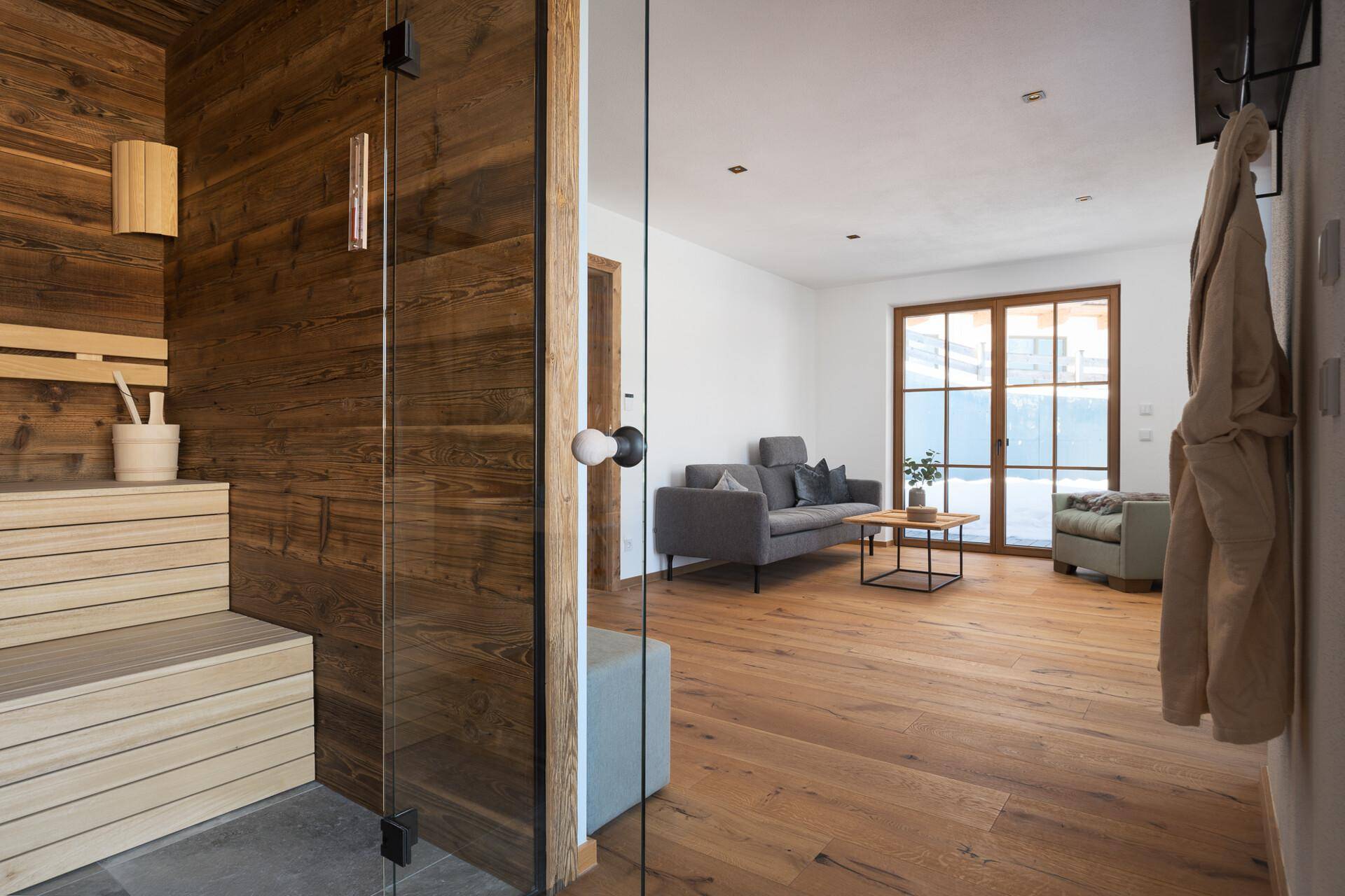 Wohnbereich mit Holzboden und direktem Zugang zu einer privaten Sauna, ideal zur Entspannung.