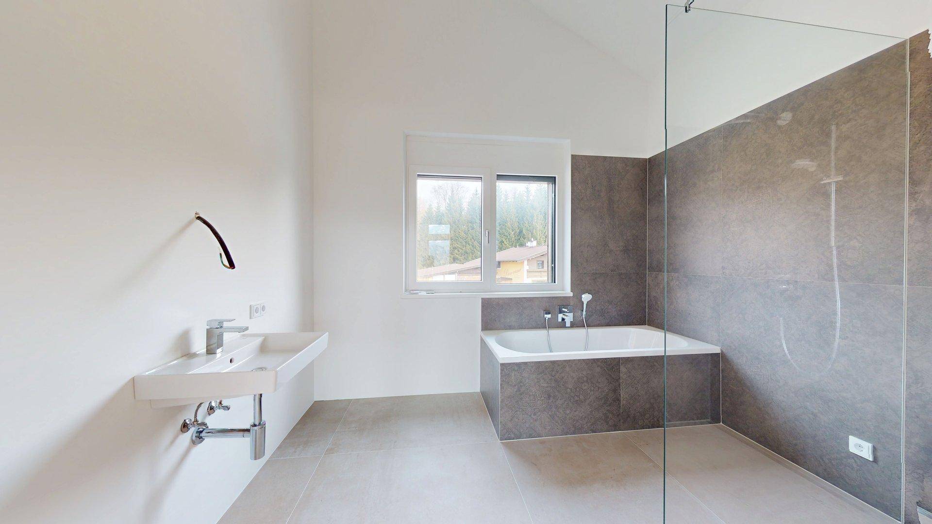 Helles Badezimmer mit modernem Waschtisch, Badewanne und großem Fenster.