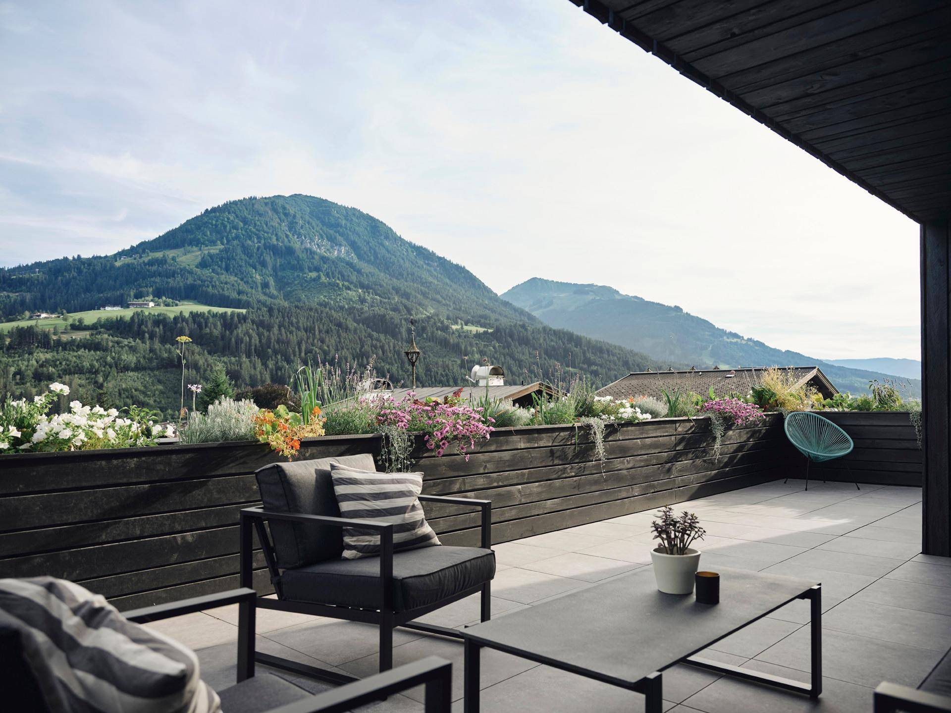 Sonnige Terrasse mit modernen Möbeln und atemberaubendem Panoramablick auf die Berge und das Tal.
