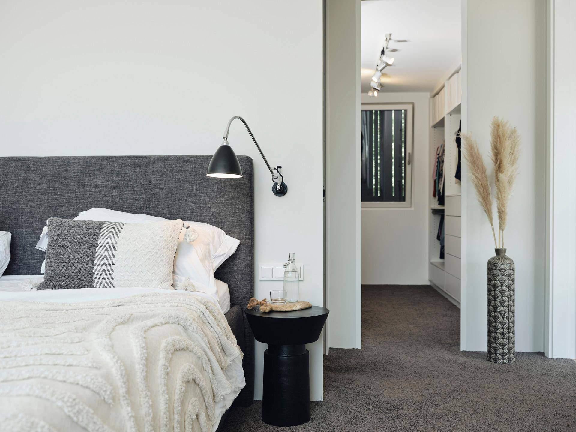 Schlafzimmer mit Teppichboden und Zugang zu einem begehbaren Kleiderschrank, modern eingerichtet.