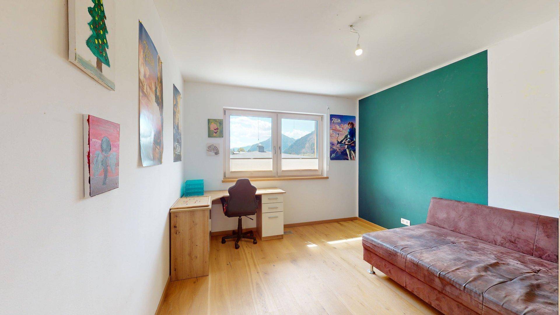 Funktionales Arbeitszimmer mit Schreibtisch, Sofa und Blick auf die umliegende Natur.