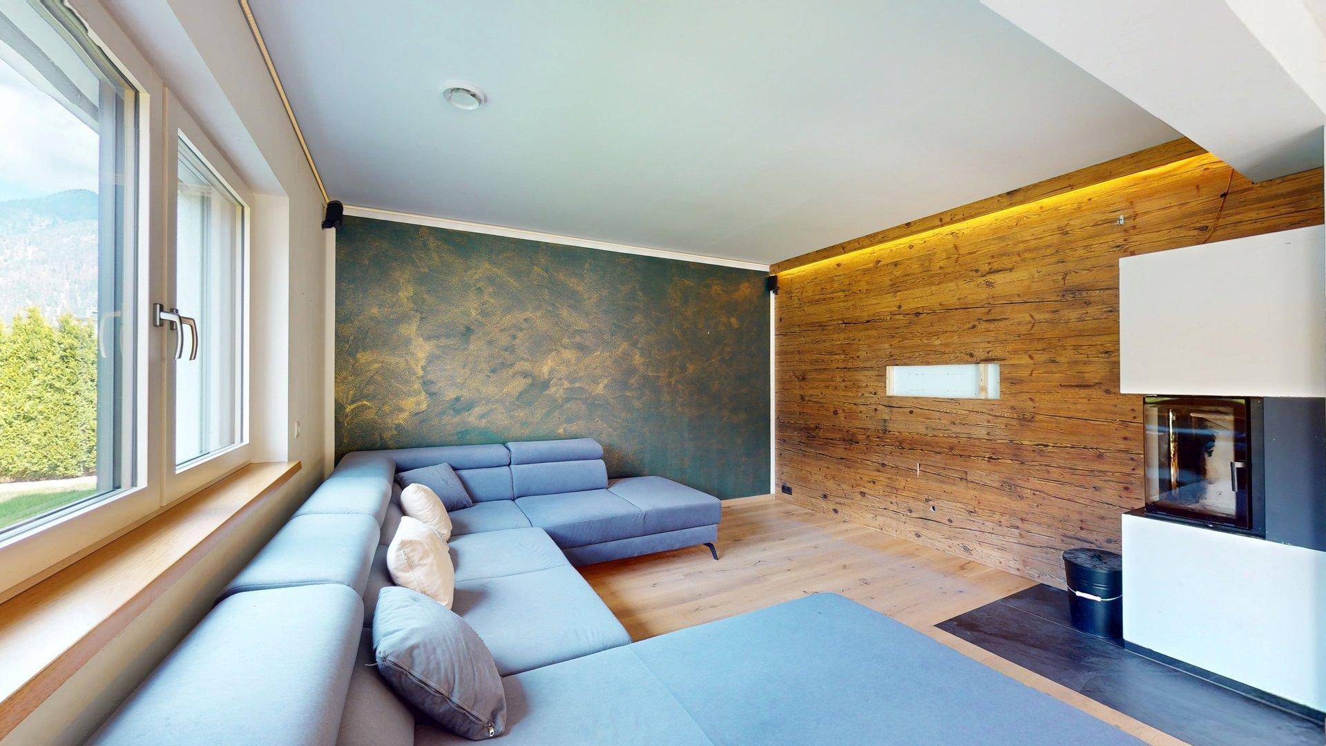 Stilvolles Wohnzimmer mit Holzwand, Kamin und bequemer Couch für entspannte Abende.