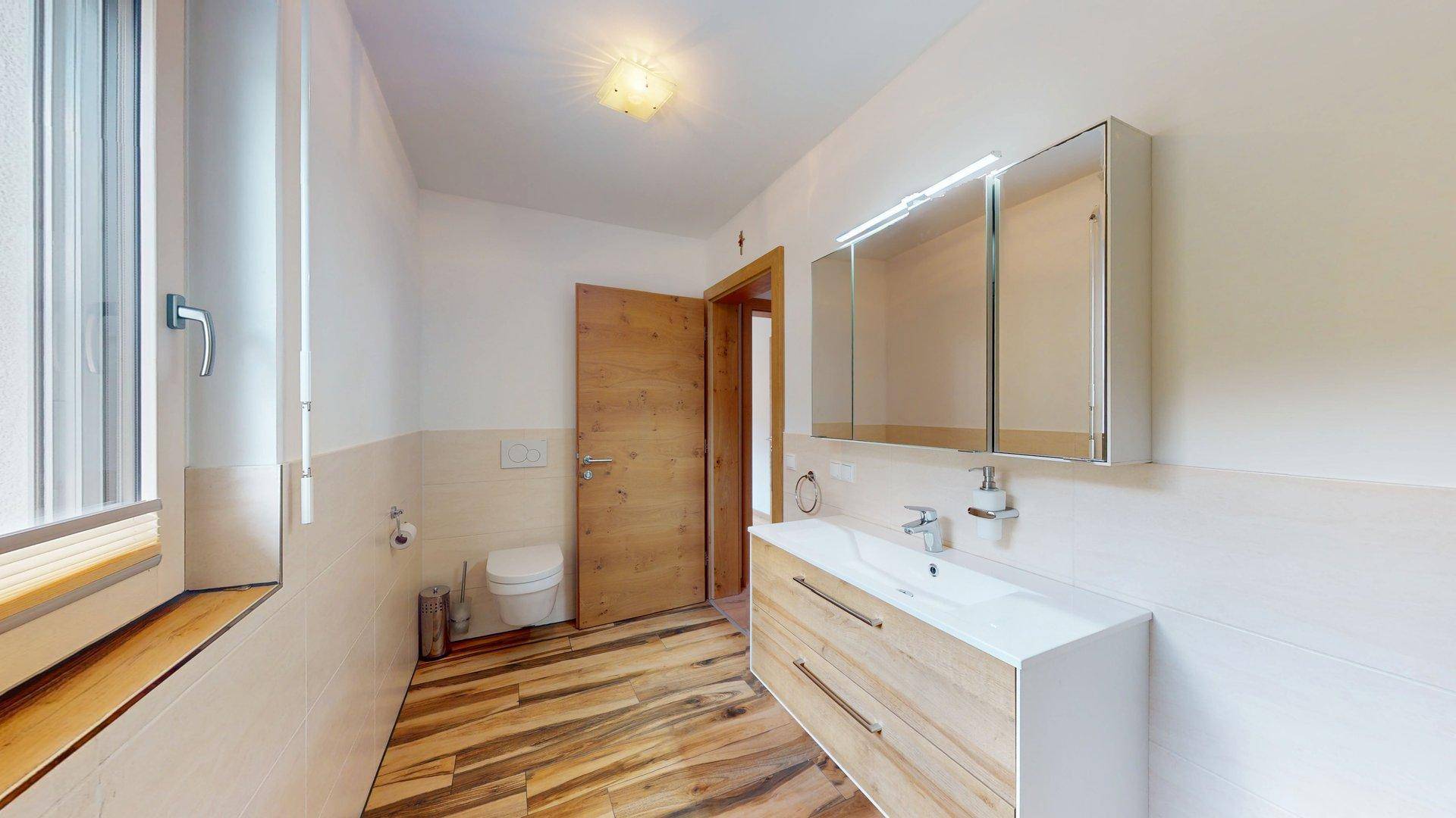 Helles Badezimmer mit modernem Waschtisch, Dusche und Fenster für natürliche Belüftung.