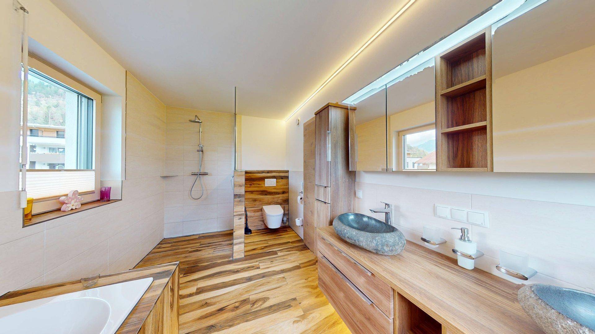 Modernes Badezimmer mit Holzboden, begehbarer Dusche, Badewanne und Doppelwaschbecken.