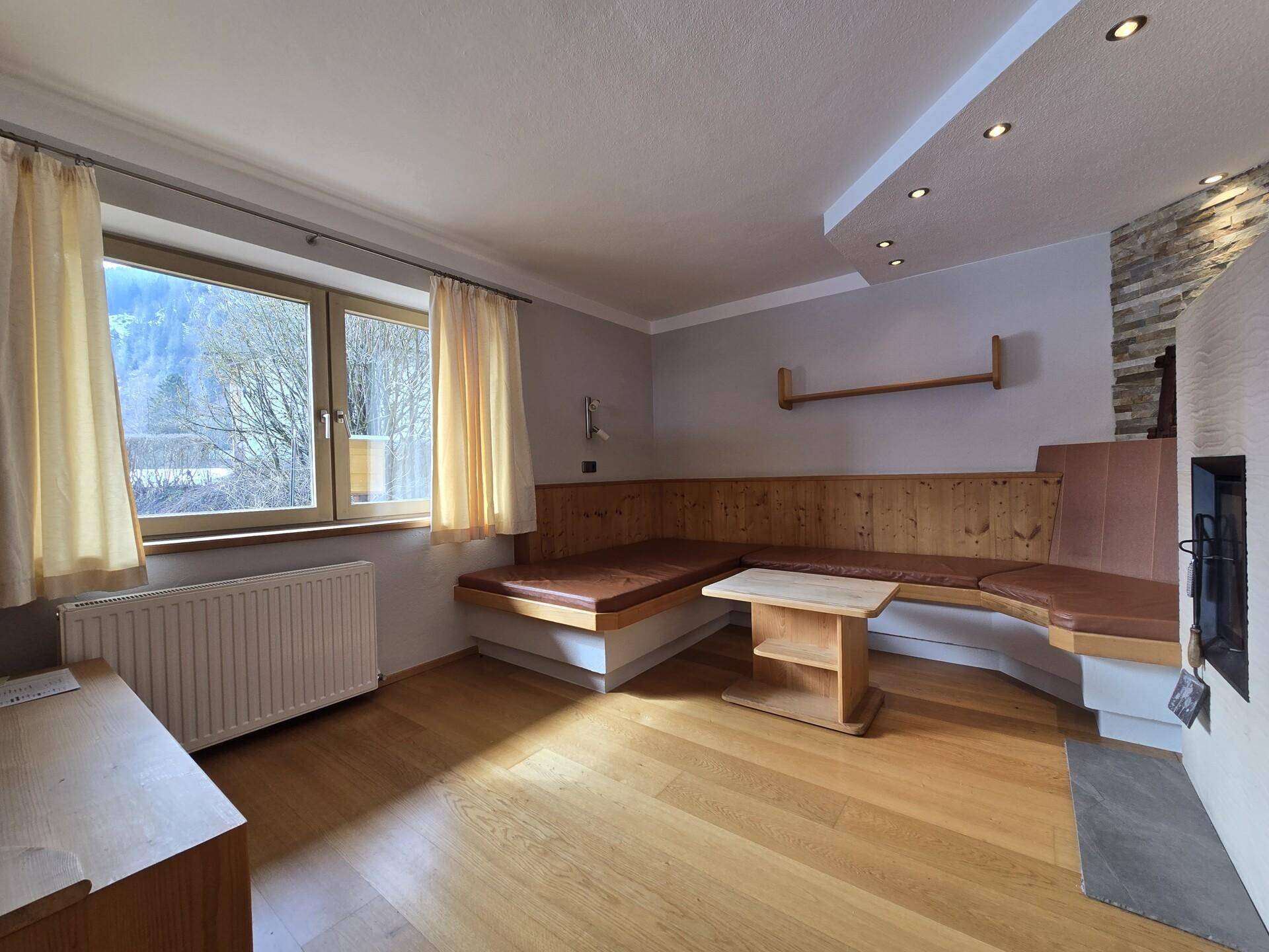 Helles Wohnzimmer mit Holzboden, bequemen Sitzgelegenheiten und Blick ins Grüne.