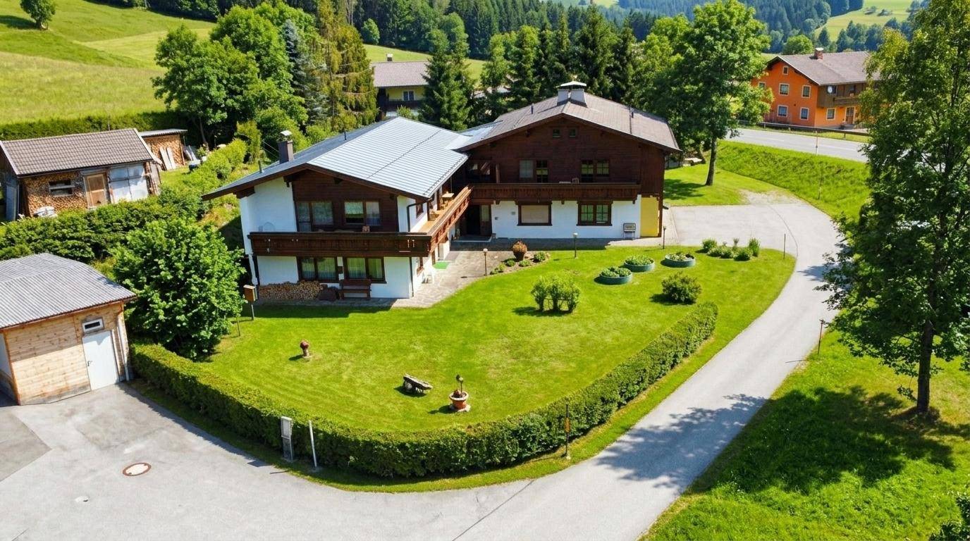 Luftaufnahme des Anwesens mit großem Garten, Zufahrt und umliegender Berglandschaft.