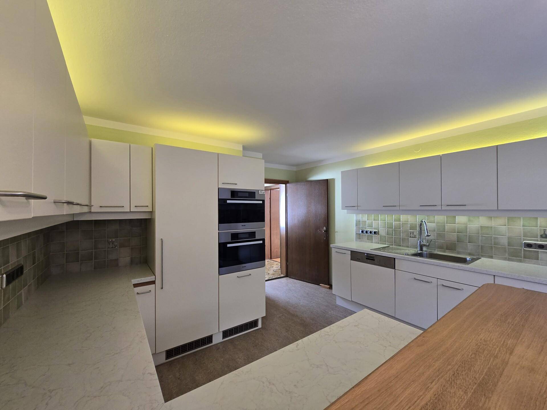 Moderne Einbauküche mit weißen Fronten, hochwertigen Geräten und viel Stauraum.