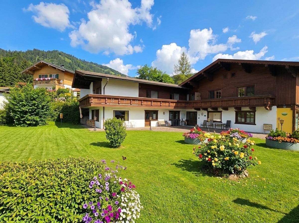 Charmantes Alpenhaus mit blühenden Blumenbeeten und weitläufigem Rasenbereich.