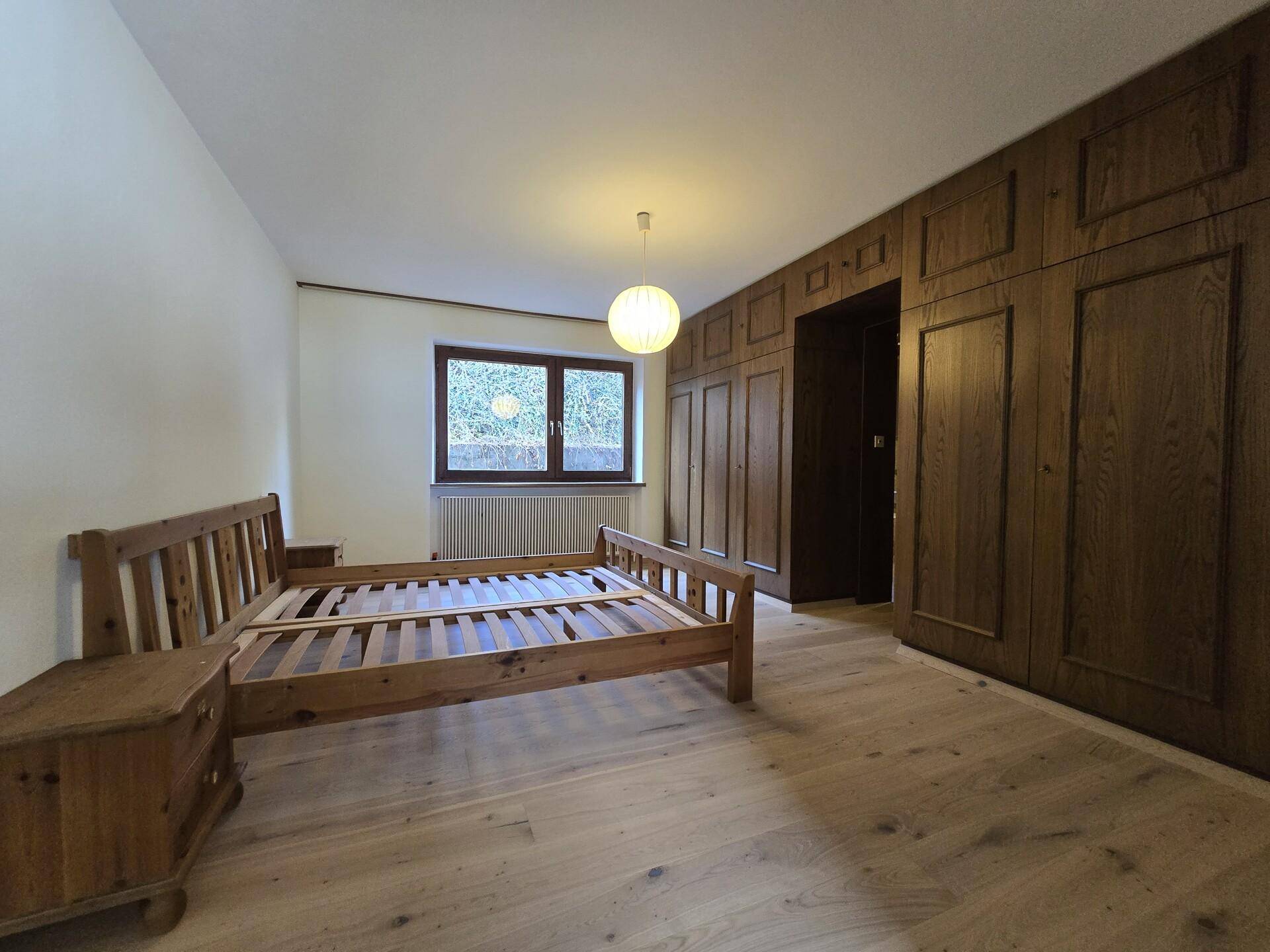 Schlafzimmer mit Holzbett, Einbauschränken und Parkettboden.