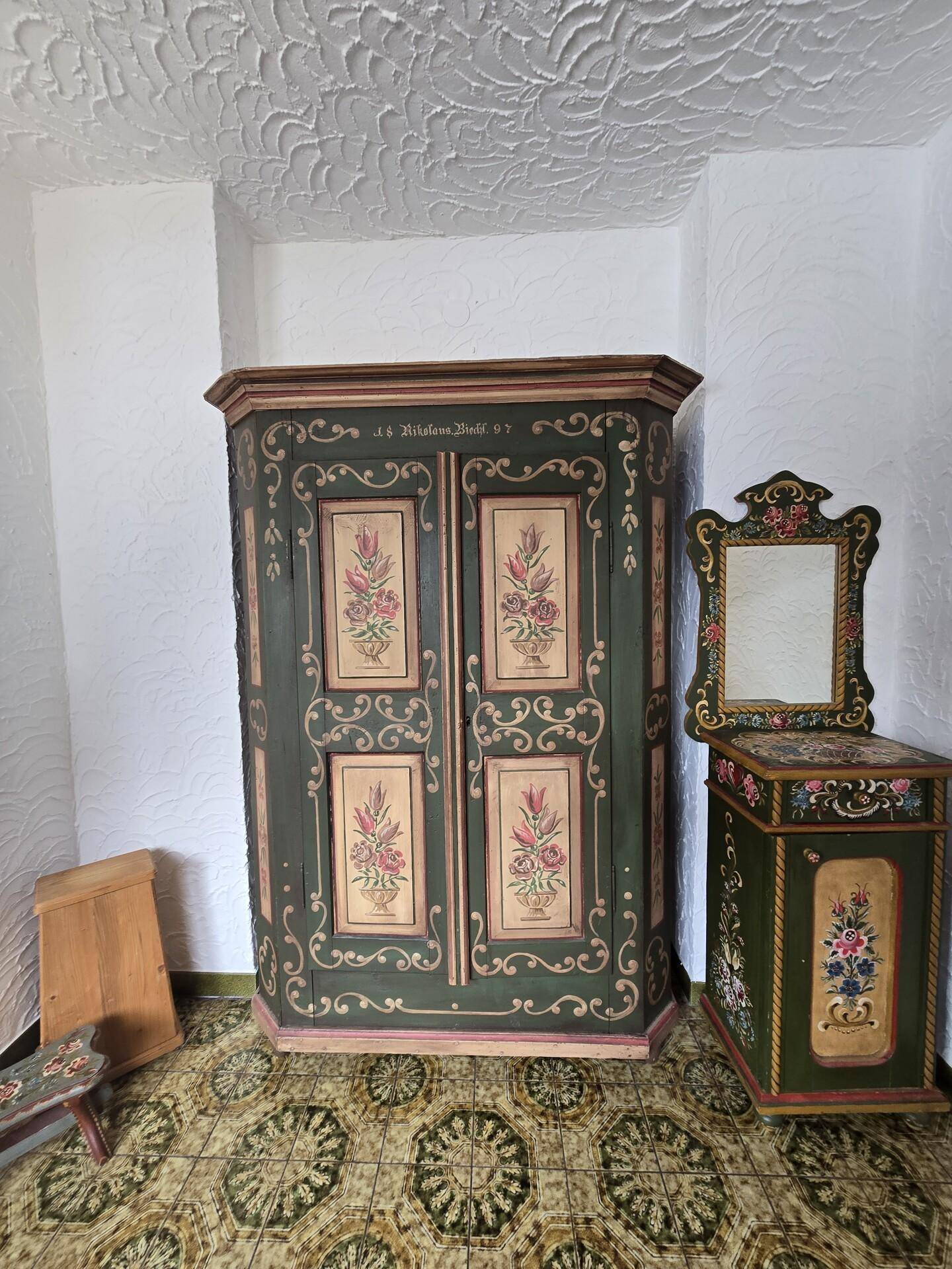 Flur oder Abstellraum mit traditionellem, bemaltem Schrank und Spiegel.