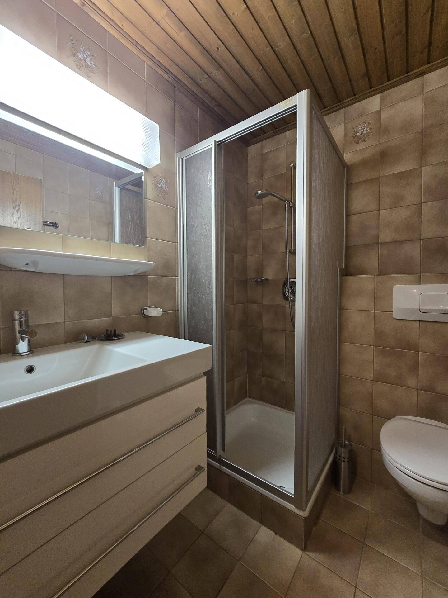 Badezimmer mit Duschkabine, Waschbecken und WC.