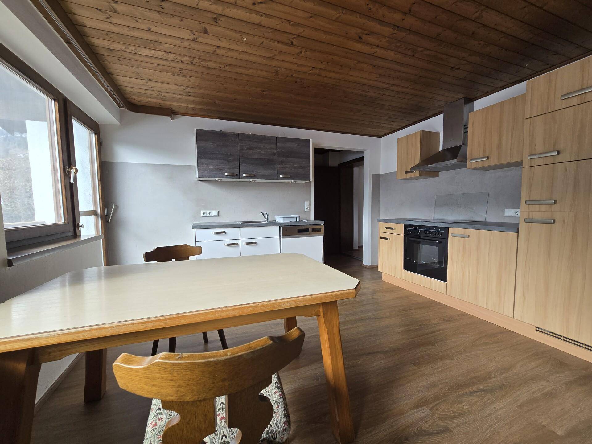 Moderne Küche mit Holzelementen, Essbereich und Laminatboden.