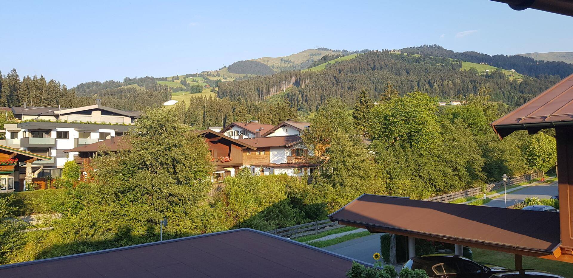 Weitblick über die umliegende Wohnbebauung und grüne Berglandschaft unter blauem Himmel.