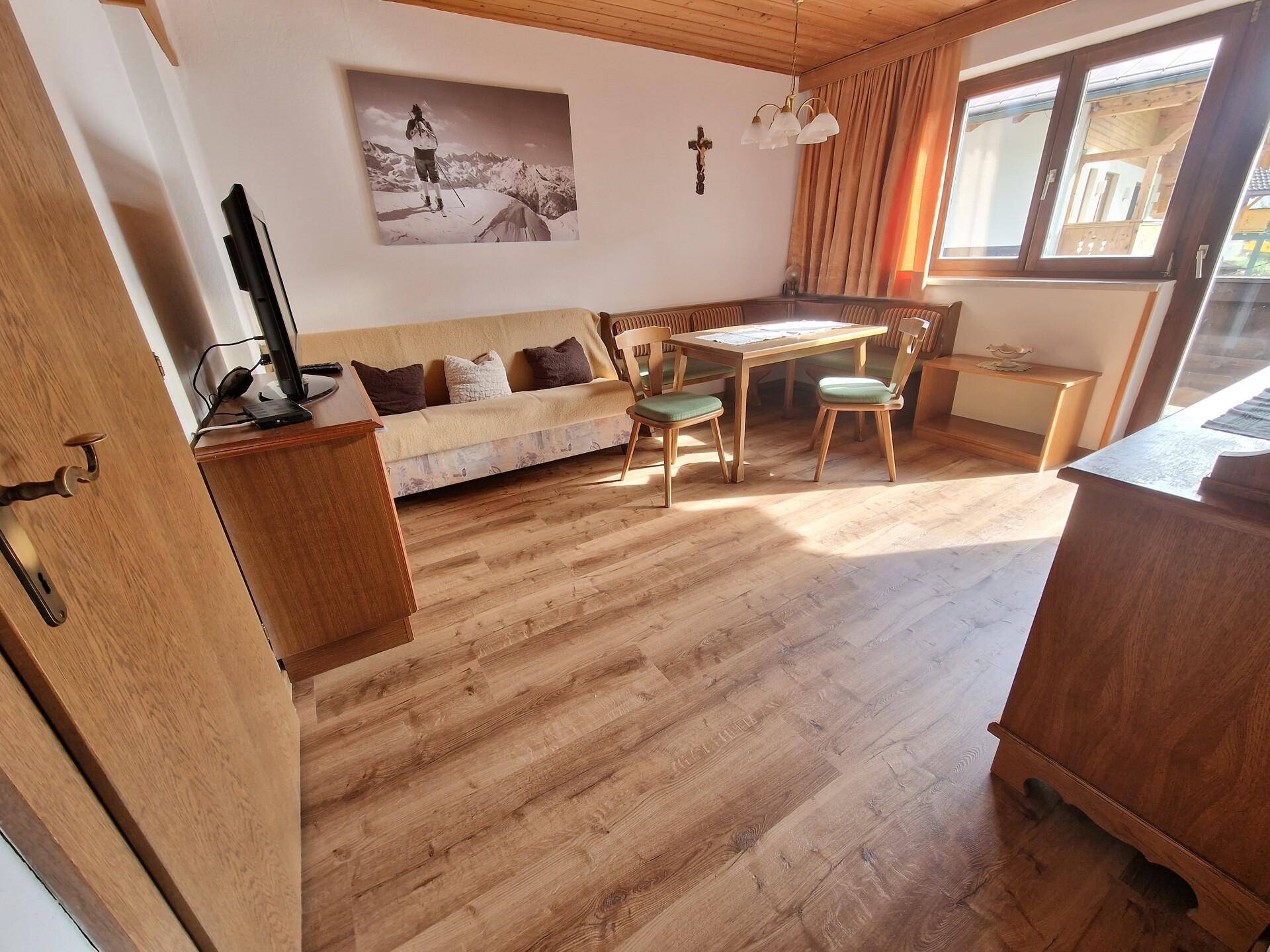 Gemütlicher Wohn-Essbereich mit Holzboden, Eckbank und traditionellen Möbeln.