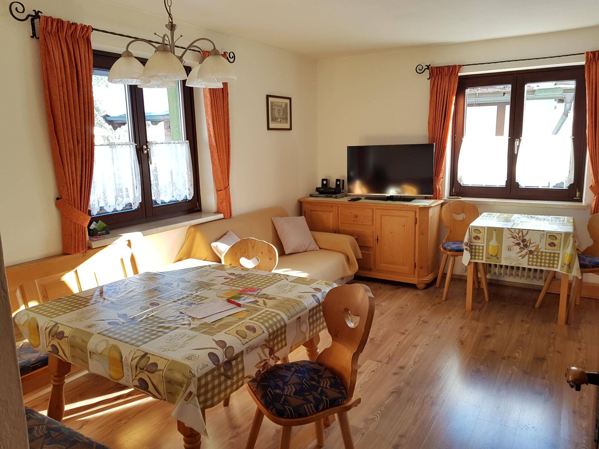 Gemütlicher Wohn-Essbereich im Landhausstil mit Holzboden, Esstisch und Sofa.