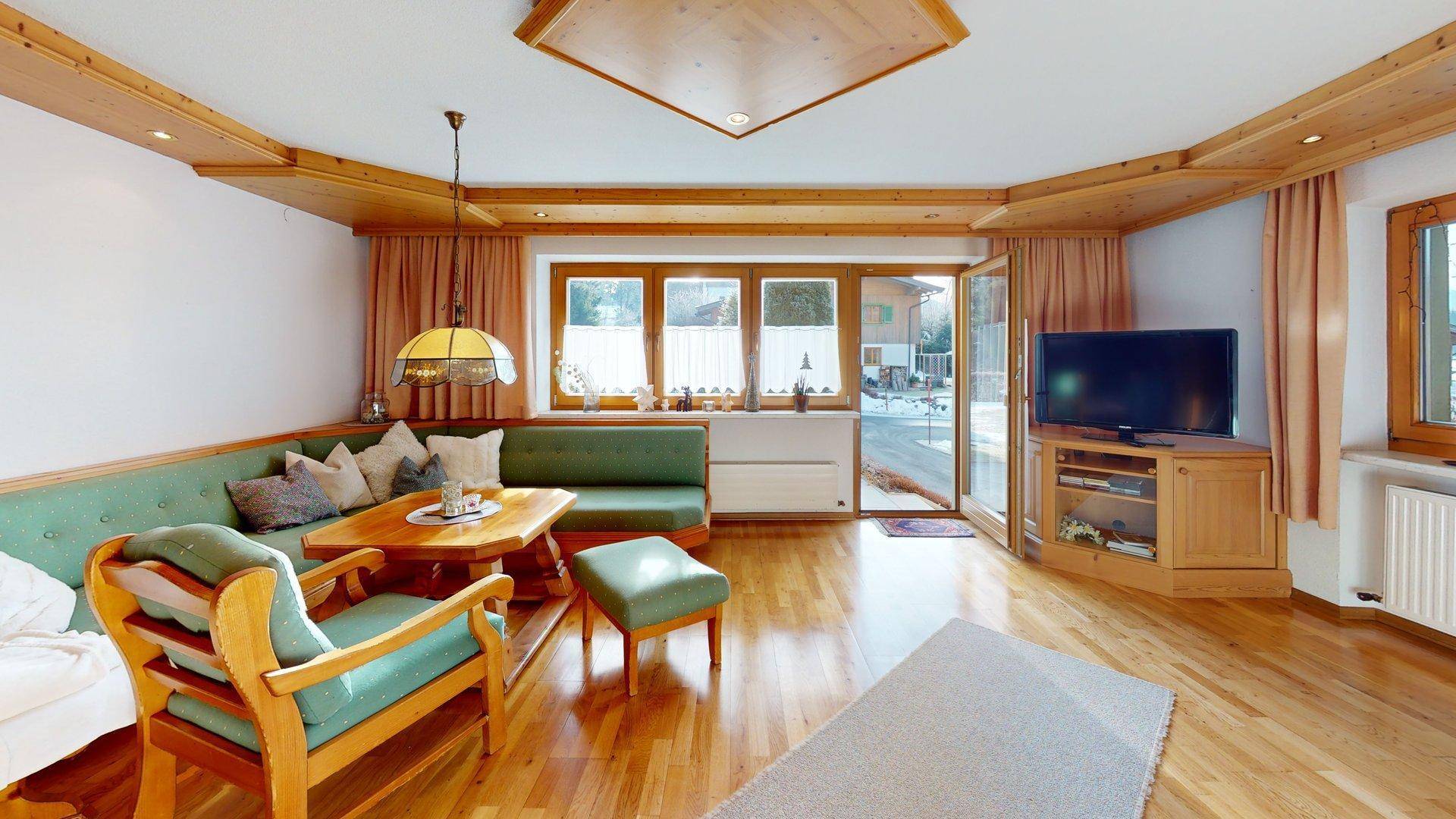 Helles Wohnzimmer mit Holzboden, bequemer Sitzgruppe und Zugang zur Terrasse.