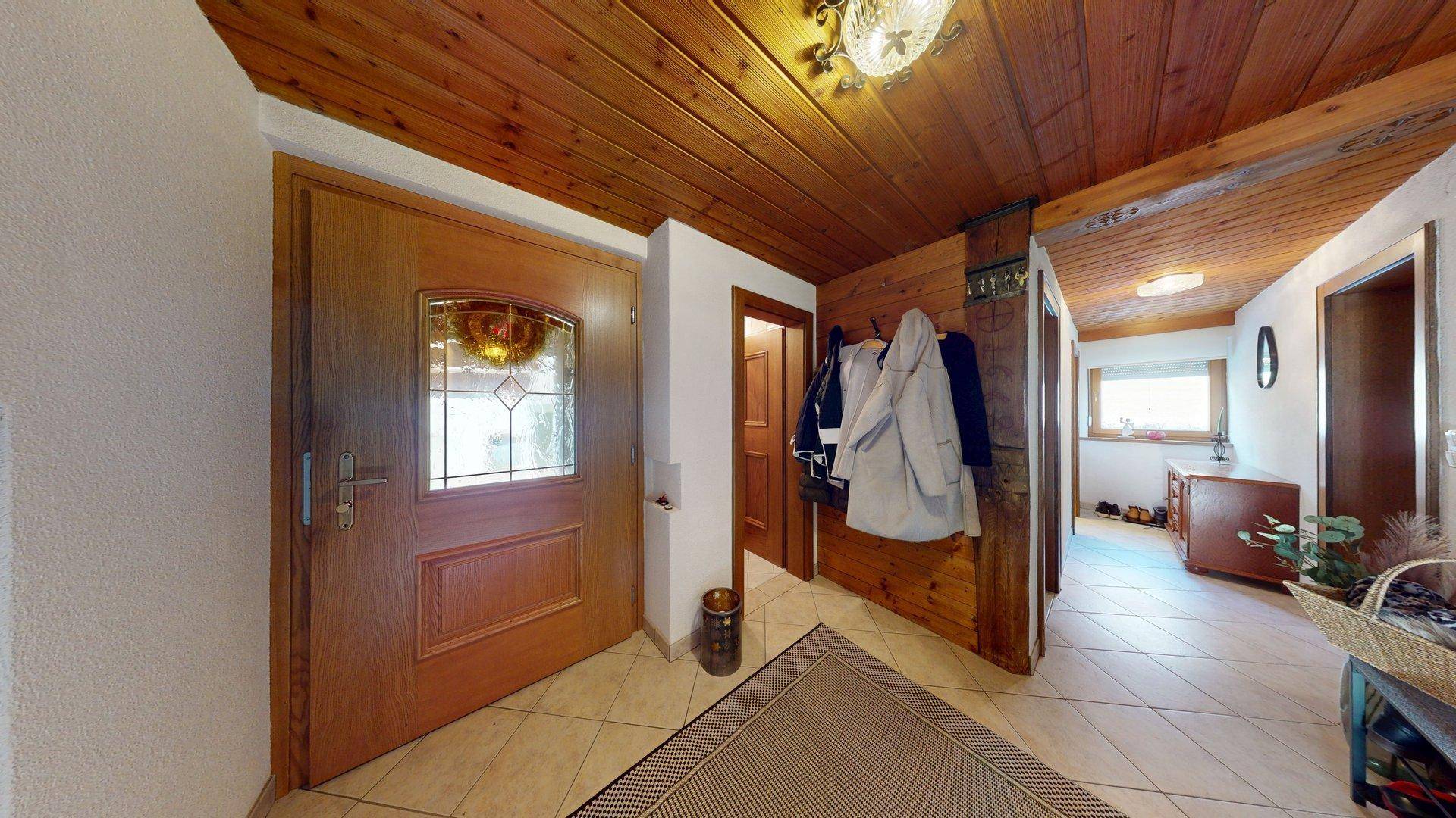 Eingangsbereich mit Holzdecke, Fliesenboden und Garderobe.