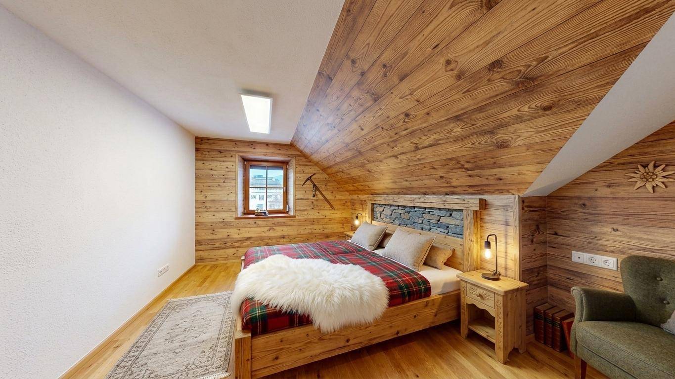 Schlafzimmer im alpinen Stil mit Holzwänden, Doppelbett und Fenster unter Dachschräge.