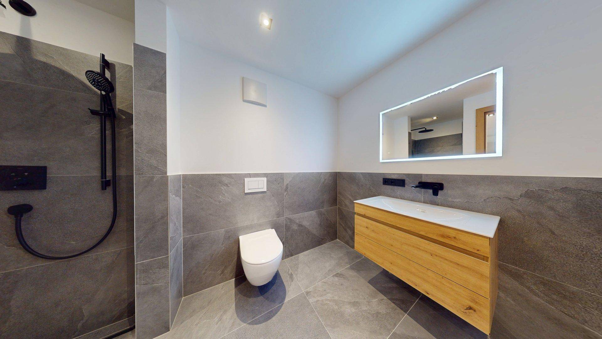 Modernes Badezimmer mit grauen Fliesen, Holzwaschtisch und begehbarer Dusche.