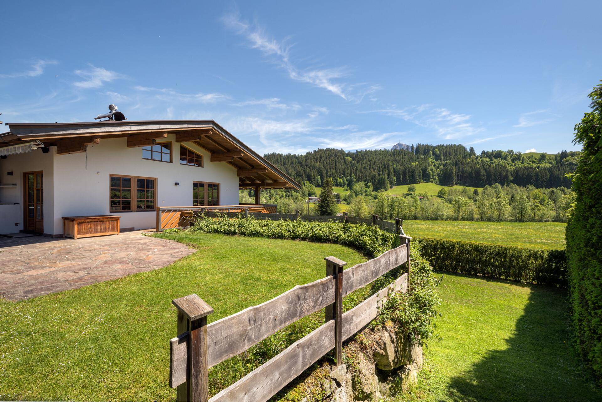 Gepflegter Gartenbereich mit Rasenfläche und Terrasse, umgeben von grünen Hecken und Natur.