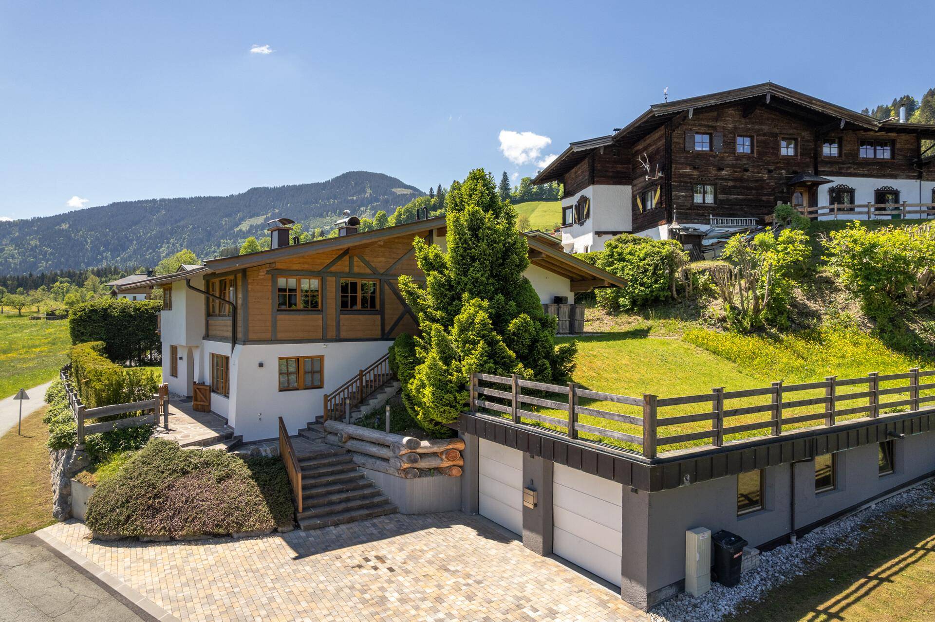 Ansicht des Hauses mit Doppelgarage und gepflasterter Auffahrt in sonniger Hanglage.