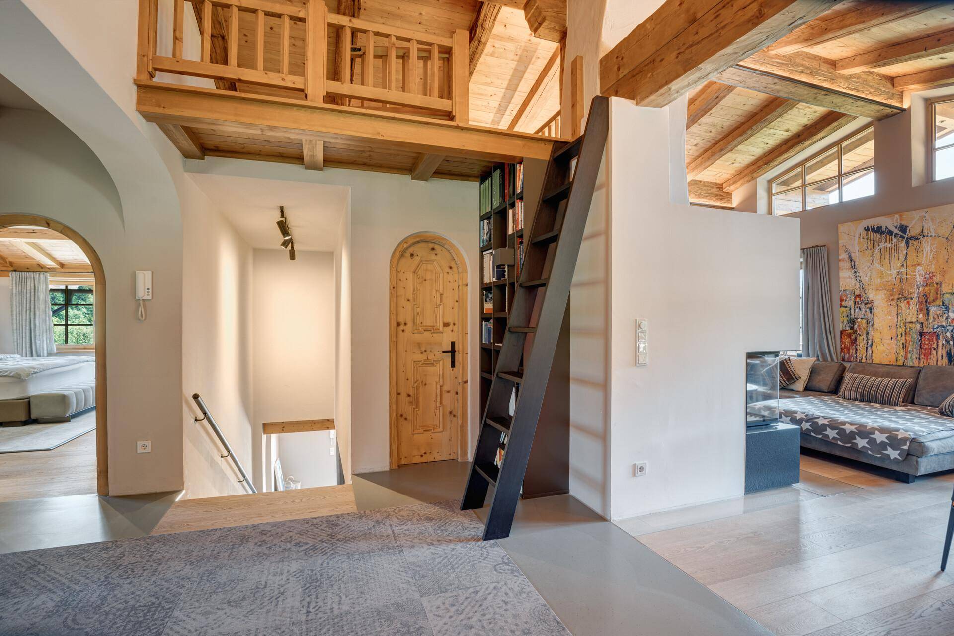 Heller Flurbereich mit Holztreppe, Zugang zu einer Galerie und rustikalen Holztüren.