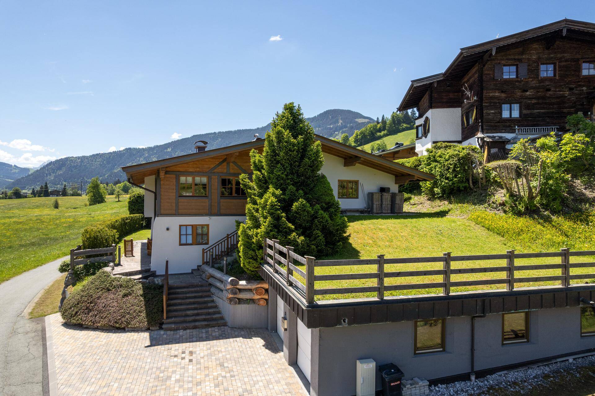 Ansicht des Hauses mit Doppelgarage und gepflasterter Auffahrt in sonniger Hanglage.