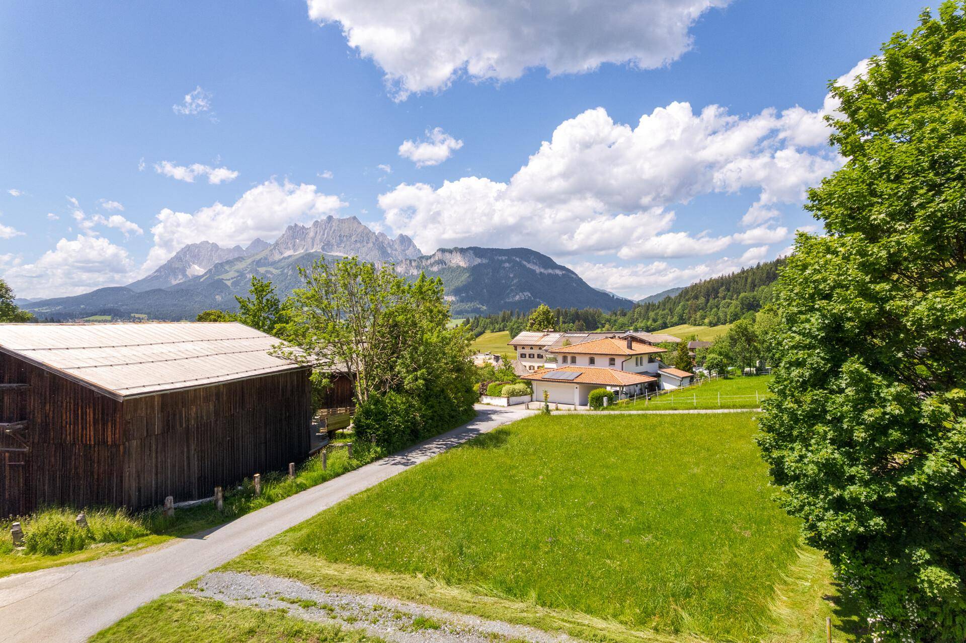 Herrliche Aussicht auf die Bergwelt, umgeben von saftigen Wiesen und vereinzelten Gebäuden in der Ferne.