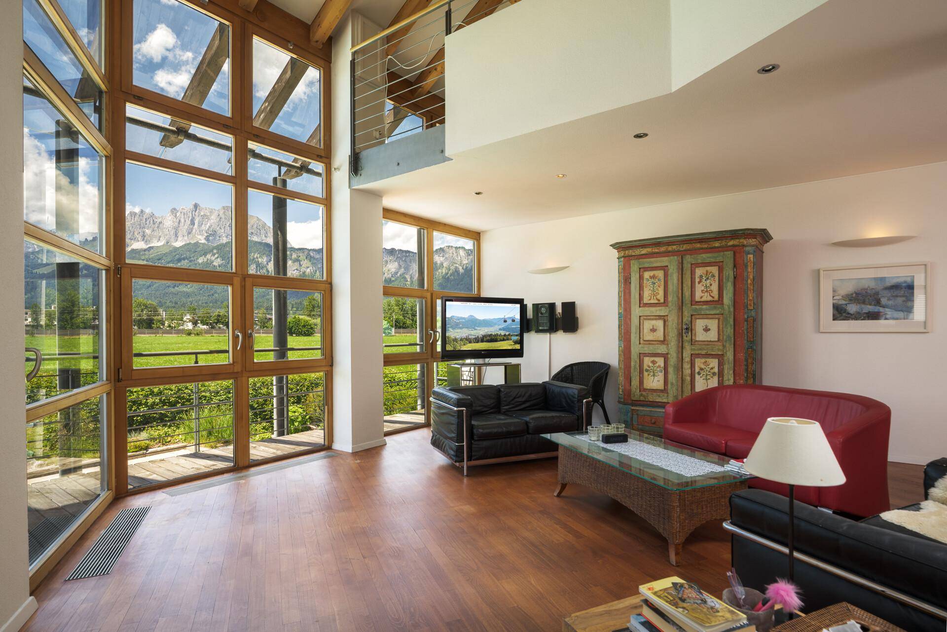 Helles Wohnzimmer mit großen Fenstern, die einen atemberaubenden Blick auf die Berglandschaft bieten.