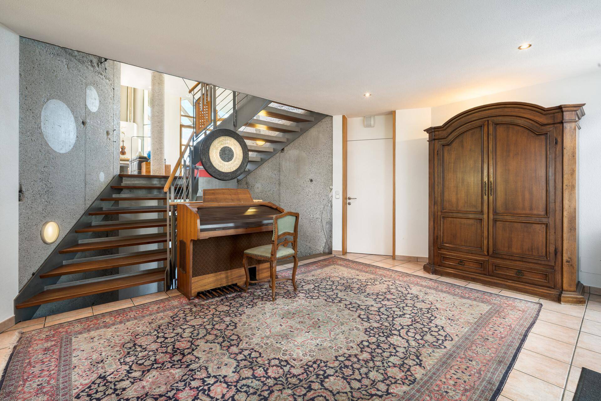 Eingangsbereich mit Holztreppe, Teppich und rustikalem Holzschrank, der zum Obergeschoss führt.