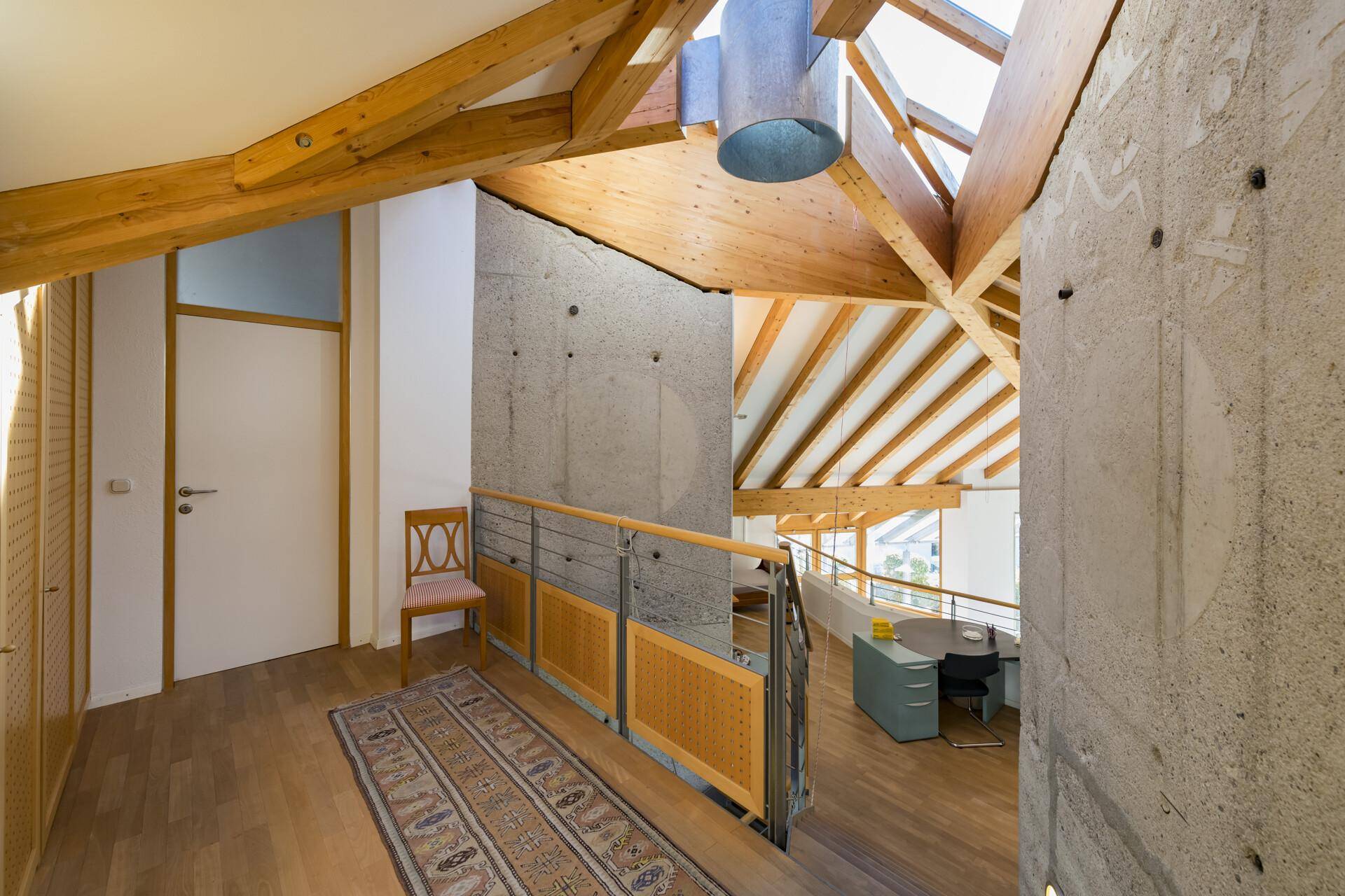 Heller Flur mit Holztreppe, Teppich und Zugang zu weiteren Räumen im Obergeschoss.